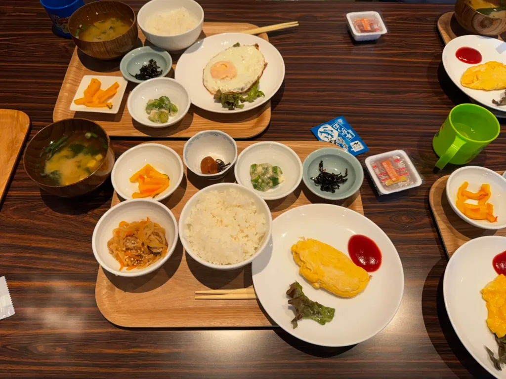 和朝食のトレー。ご飯、みそ汁、卵料理、小鉢が並ぶ